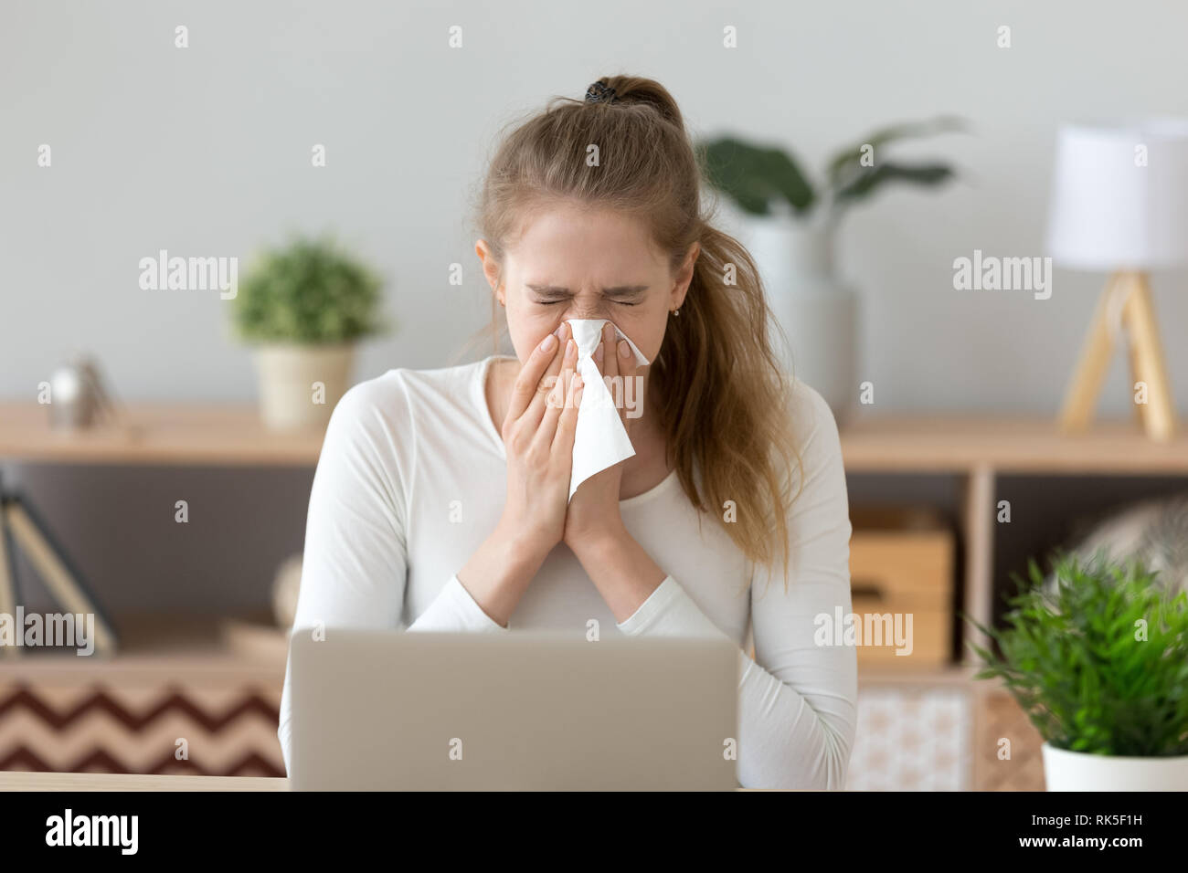 Kranke junge Frau gefangen Kälte niesen Abwischen laufende Nase Stockfoto