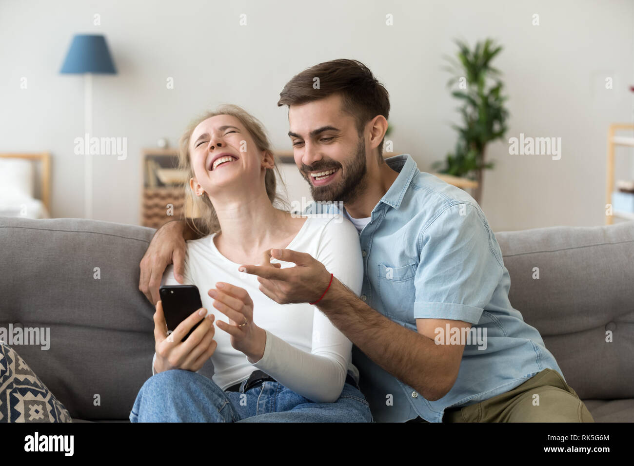 Glückliches junges Paar lachend Holding Telefon sprechen über online Witz Stockfoto