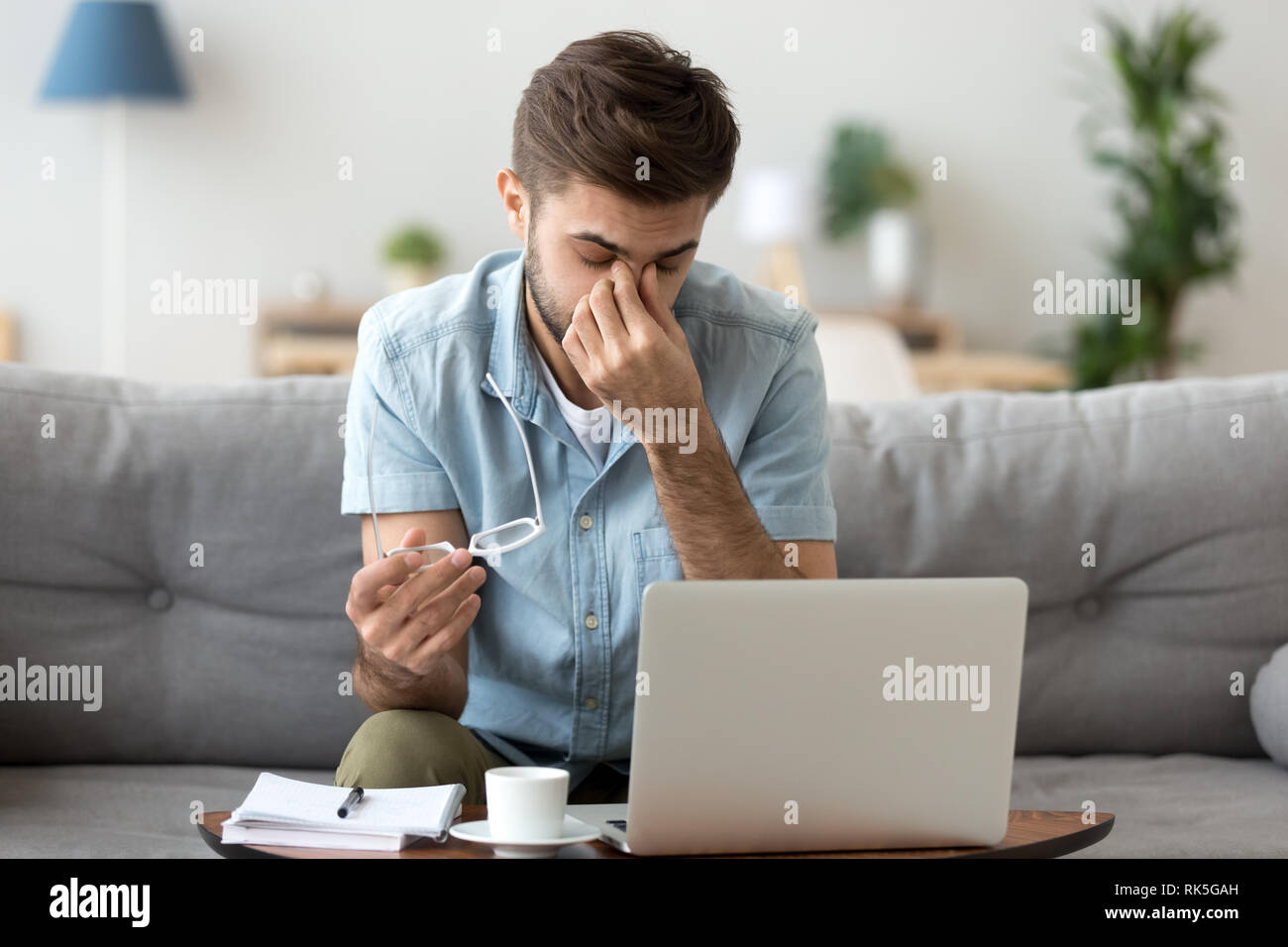 Müde junge Mann Gefühl Belastung der Augen Kopfschmerzen nach Arbeiten am Computer Stockfoto