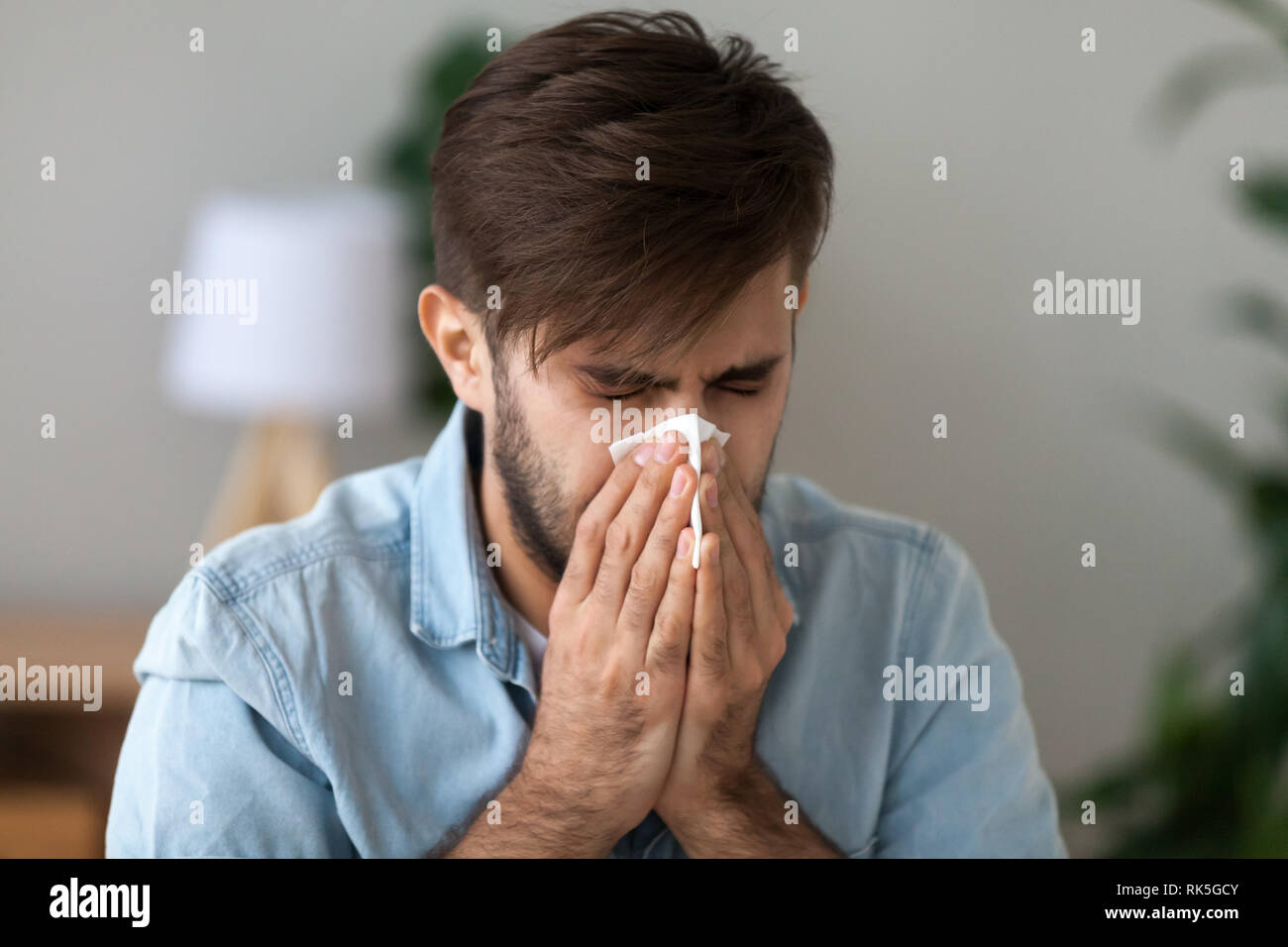 Kranken mann Grippe Allergie Schnupfen im Taschentuch die Nase blasen Stockfoto