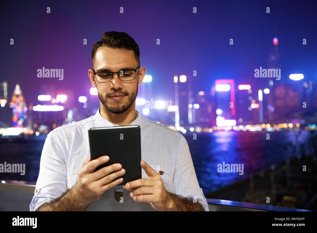 Der Mensch arbeitet mit Tablet Computer gegen Nacht Stadt. Remote arbeiten Konzept. Hongkong, China Stockfoto
