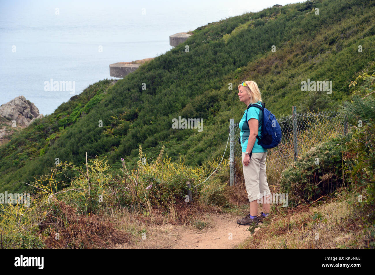 Frau Wanderer mit Blick auf das Meer durch die Versteckten WW 2 Deutsche Concreate Beobachtungsbunker Jerbourg Point auf dem Küstenweg von Guernsey Kanalinseln Stockfoto