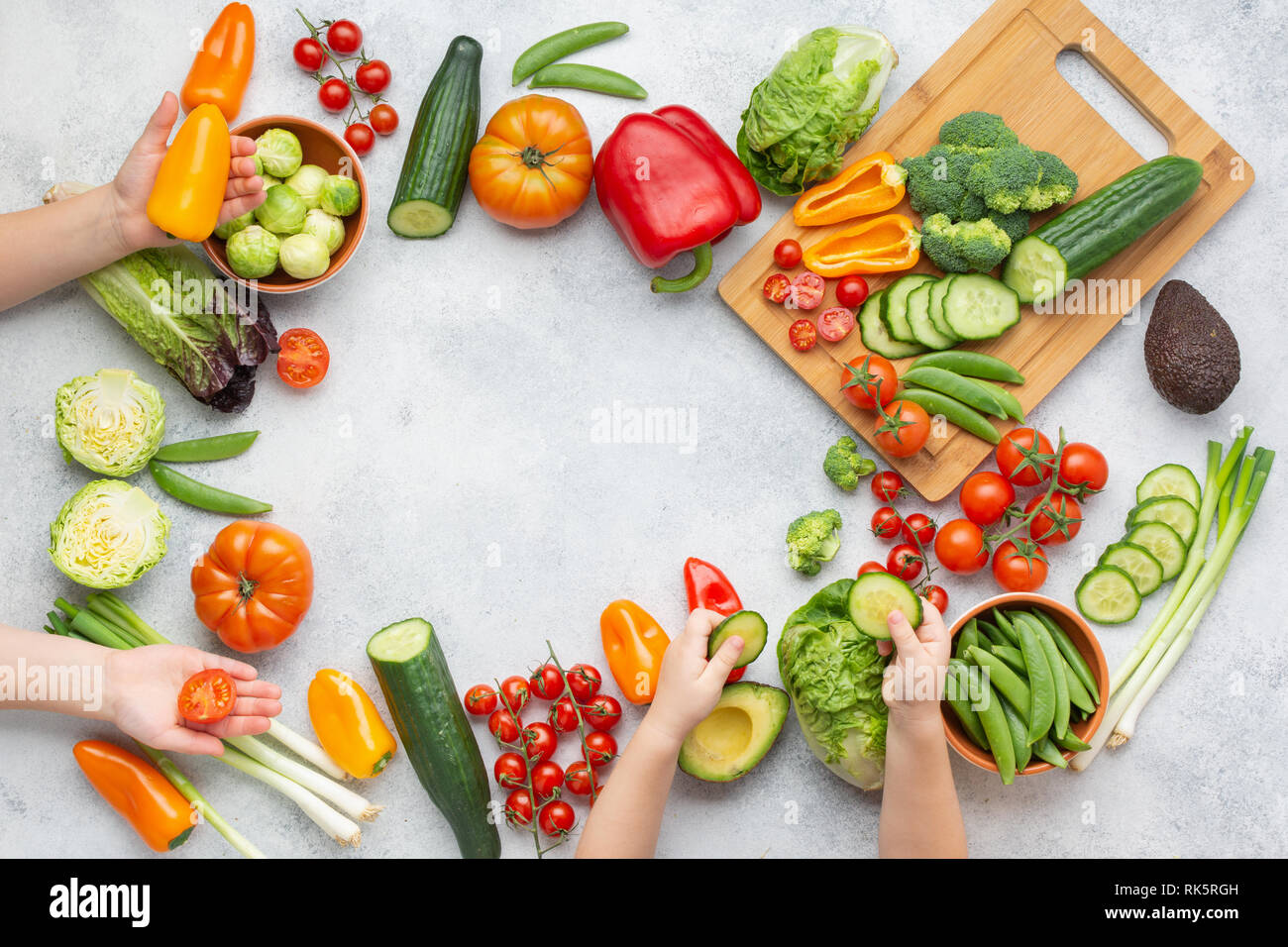Ansicht von oben von Gemüse, Tomaten Gurken salat Paprika Frühlingszwiebel Brokkoli Erbsen auf dem weißen Tisch, die Hände die Kinder halten essen, Kopieren, selektiven Fokus Stockfoto