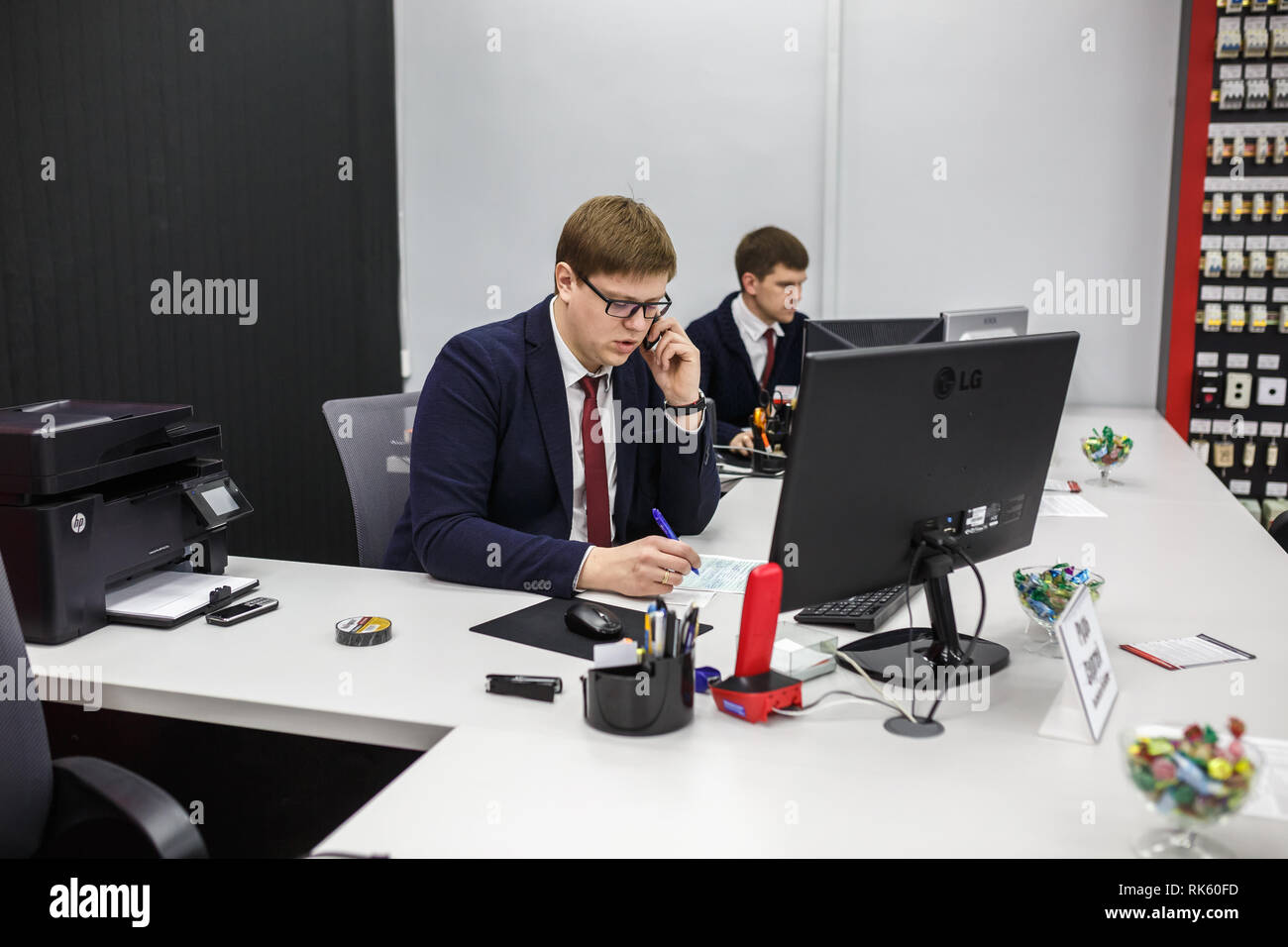 GRODNO, Weißrussland - AUGUST 2017: Mitarbeiter, um den Anruf zu beantworten im Store an der Arbeit am Computer im modernen Shop Stockfoto