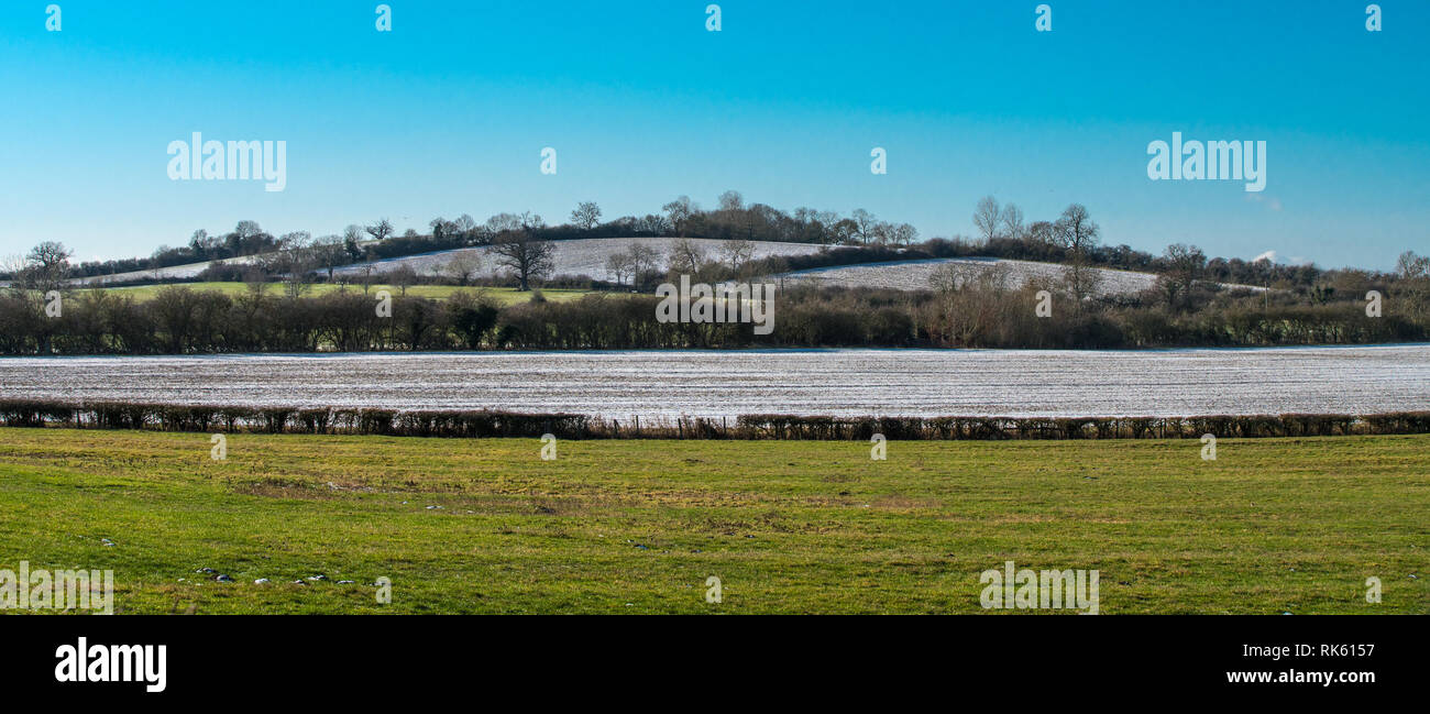 Englische Landschaft im Winter. Panorama einer sanft gerundete Hügel mit Bäumen und Feldern mit einer leichten Schneedecke auf einem hellen Winter Tag Stockfoto