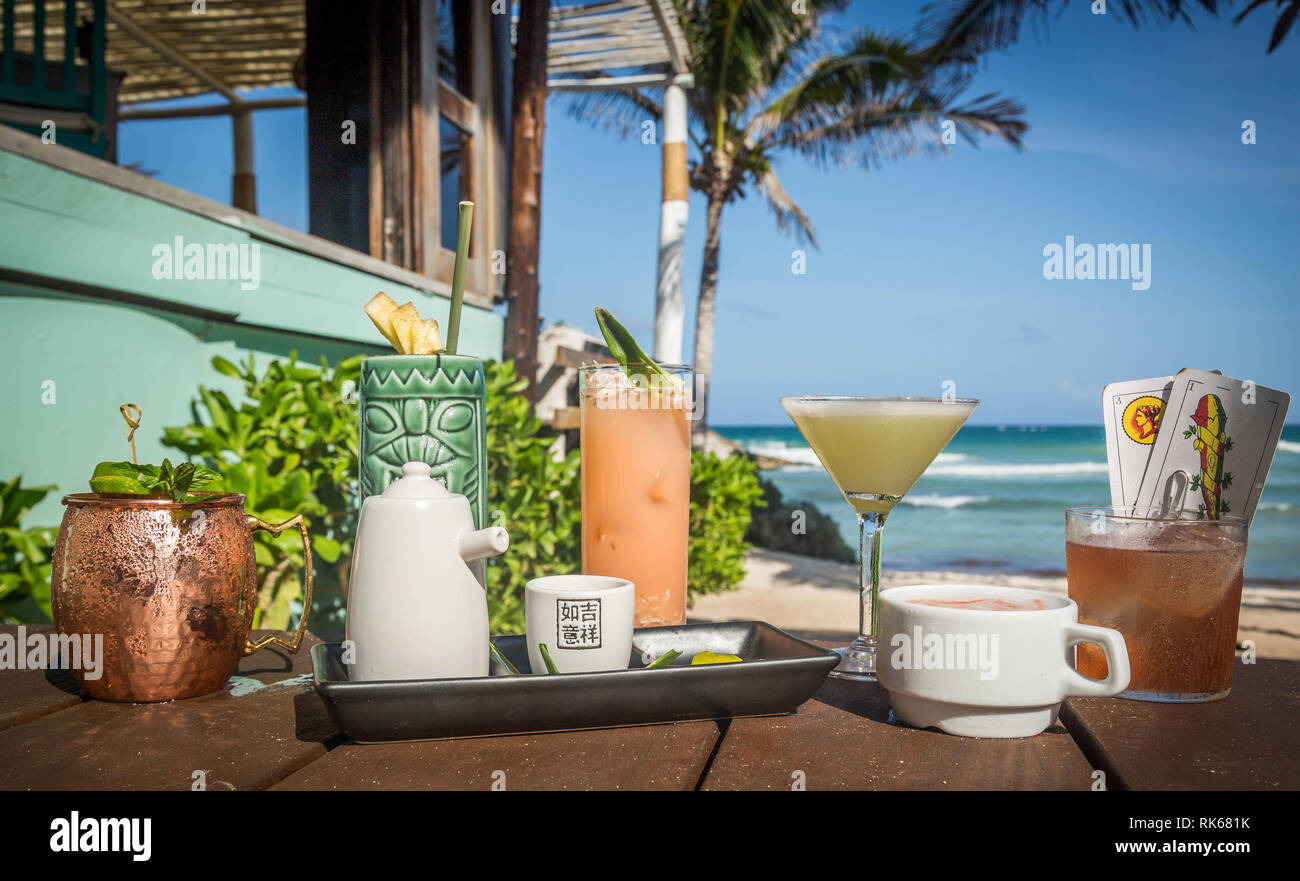 Eine Auswahl an kreativen tropische Cocktails auf einem Holzboden mit der Strand auf dem Hintergrund Stockfoto