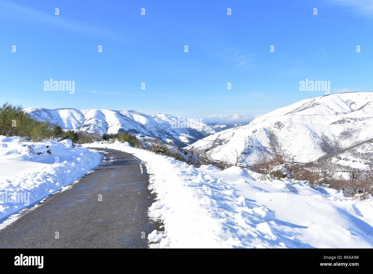 Winterlandschaft mit Straße und schneebedeckten Berge. Sonnigen Tag, blauer Himmel. Ancares Region, Provinz Lugo, Galizien, Spanien. Stockfoto