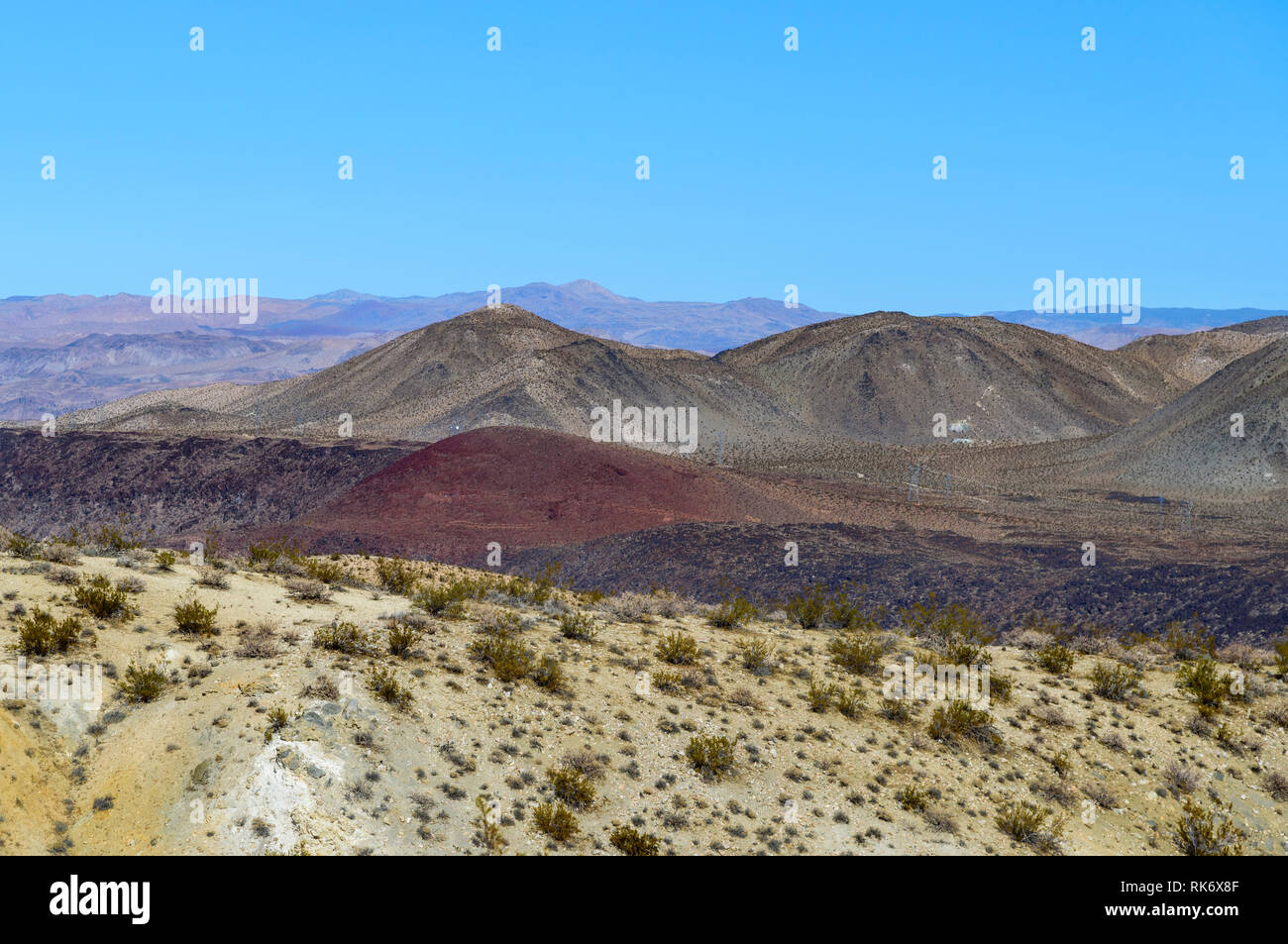 Mit Blick auf die Weiße Wüste Berge mit roten und schwarzen Hügeln hinter, unter strahlend blauem Himmel. Stockfoto