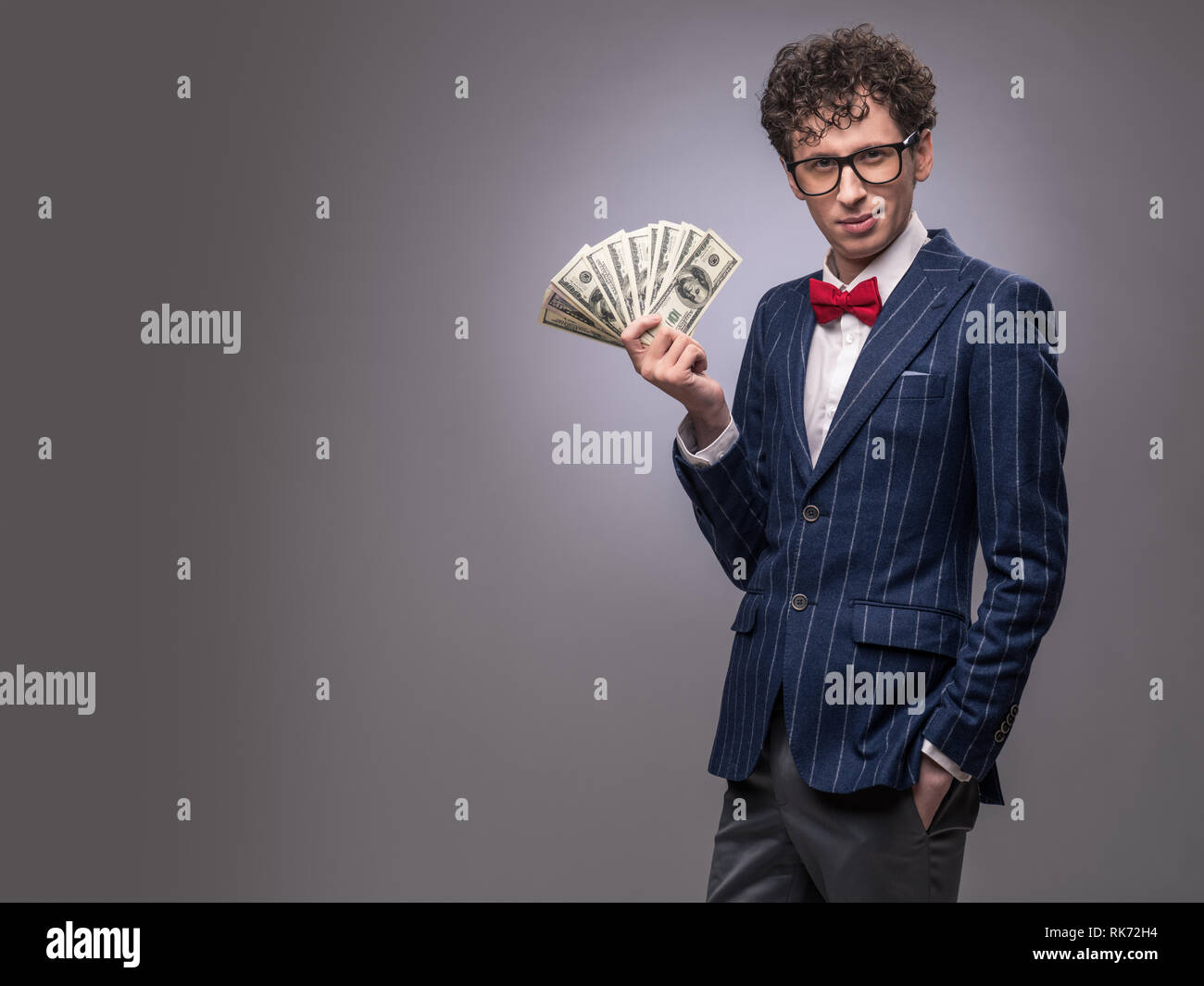 Lustiger Mann mit Lüfter Geld auf grauem Hintergrund Stockfoto