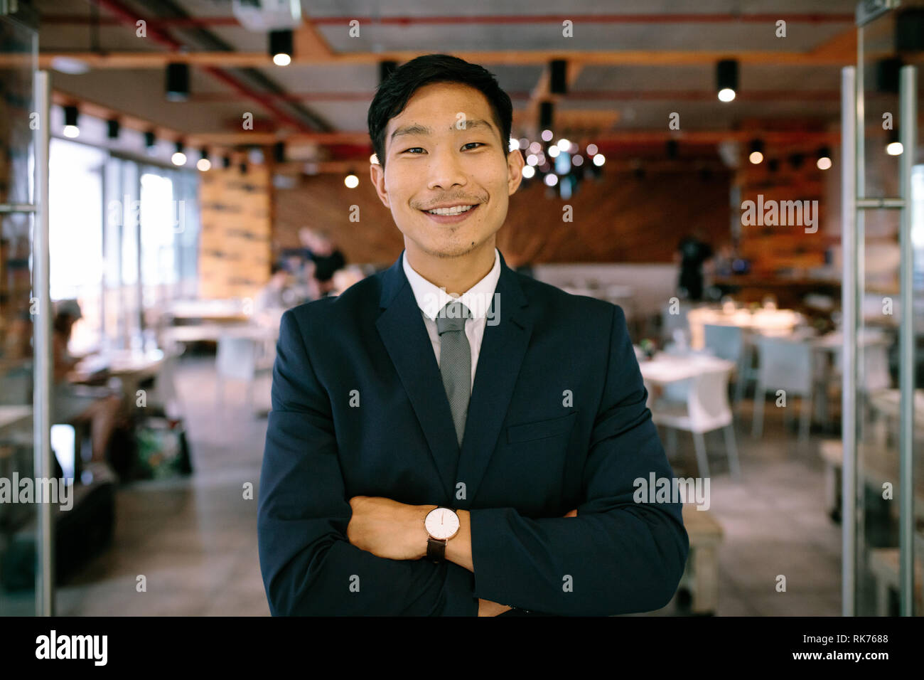 Portrait von selbstbewussten jungen Geschäftsmann an Coffee Shop. Asian Business Mann stand mit verschränkten Armen und Kamera. Stockfoto