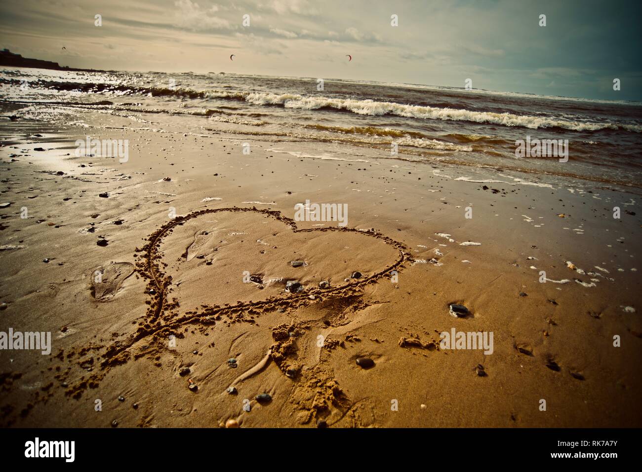 Lieben den Strand, das Meer lieben. Ein Herz in den Sand des Strandes mit der Tide, die hereinkommen, Rhosneigr, Anglesey, North Wales, UK gezeichnet Stockfoto