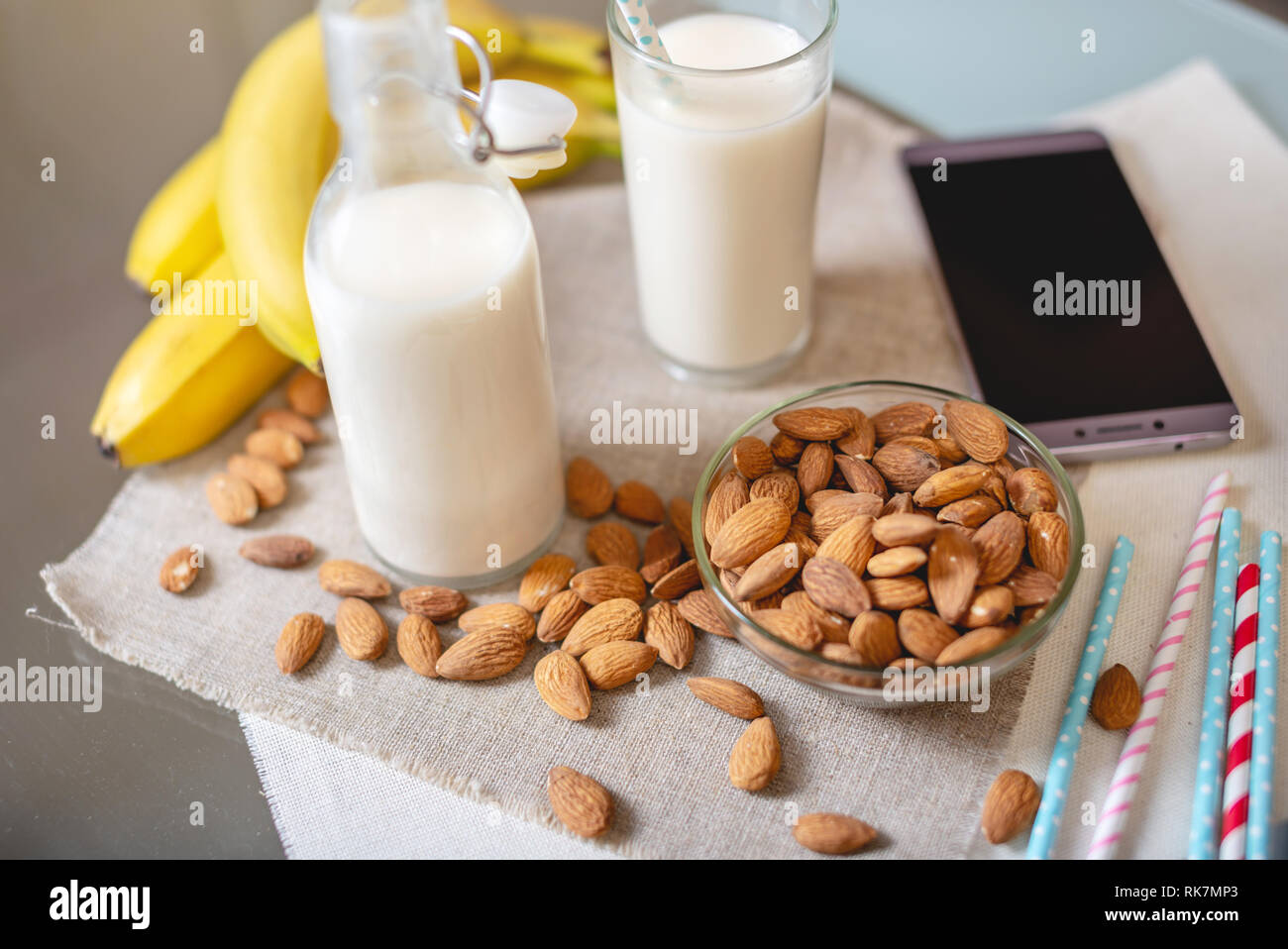 Mandel Milch in ein Glas Schale und Obst mit verstreuten Mandeln am Tisch in der Küche. Ernährung Gesunde vegetarische Produkt Stockfoto