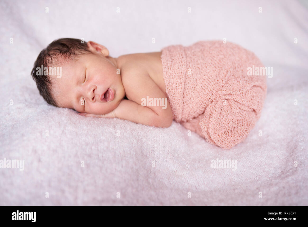 Süßes neugeborenes Baby schlafen mit offenen Mund Stockfoto