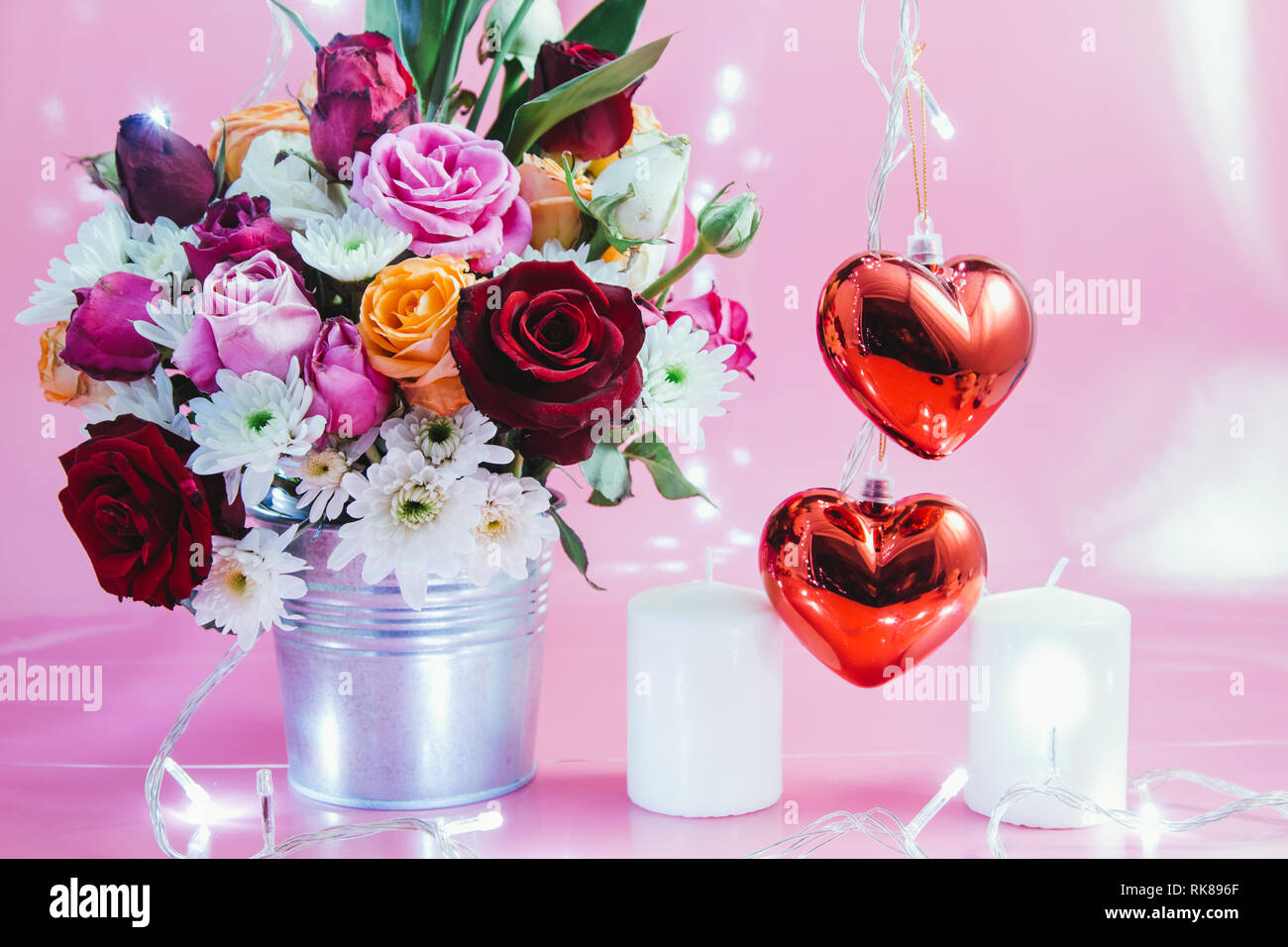 Vase Bouquet Rosen in Aluminium Schaufel und Rot glitzernden Herz mit weißen Kerzenständer auf rosa Hintergrund. Leuchtet das Licht der Liebe in Valentine da Stockfoto