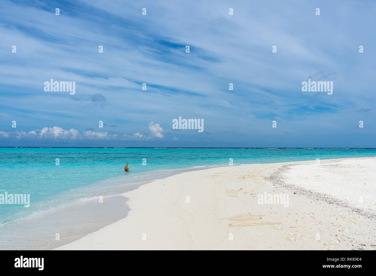Sandbank mit einer unbekannten jungen Frau im Hintergrund auf den Malediven. Stockfoto