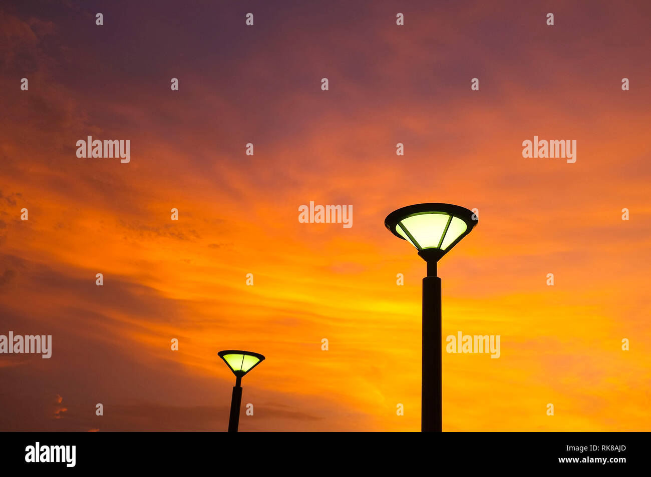 Straßenbeleuchtung gegen eine orange Himmel bei Sonnenuntergang. Stockfoto