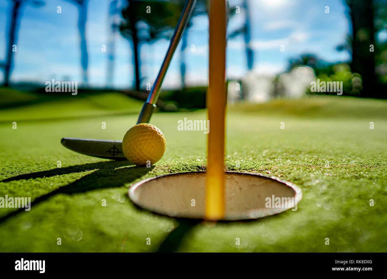 Minigolf gelben Ball mit einem Schläger in der Nähe der Bohrung bei Sonnenuntergang Stockfoto