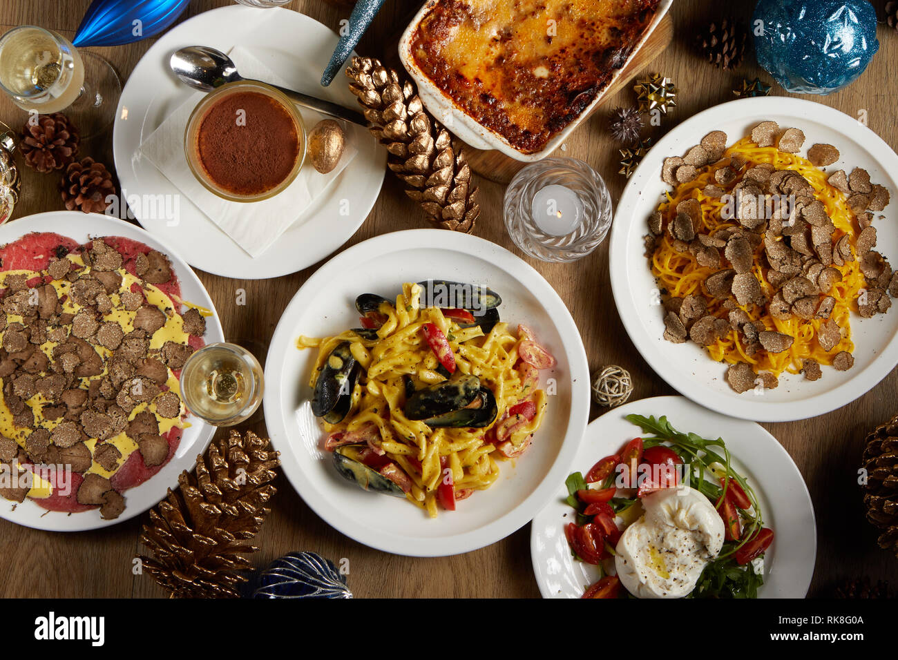 Draufsicht auf den Weihnachtstisch mit einer Auswahl an Gerichten wie Lasagne, Tagliatelle Pasta mit rasierten Trüffeln, Rindfleisch Carpaccio mit Trüffeln Stockfoto