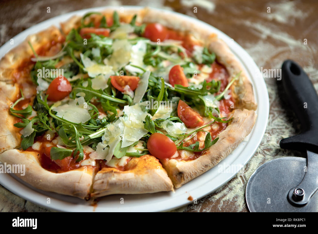 Dünne Kruste vegetarische Pizza mit Tomaten, Parmesan, Rucola auf Tomatenbasis Stockfoto