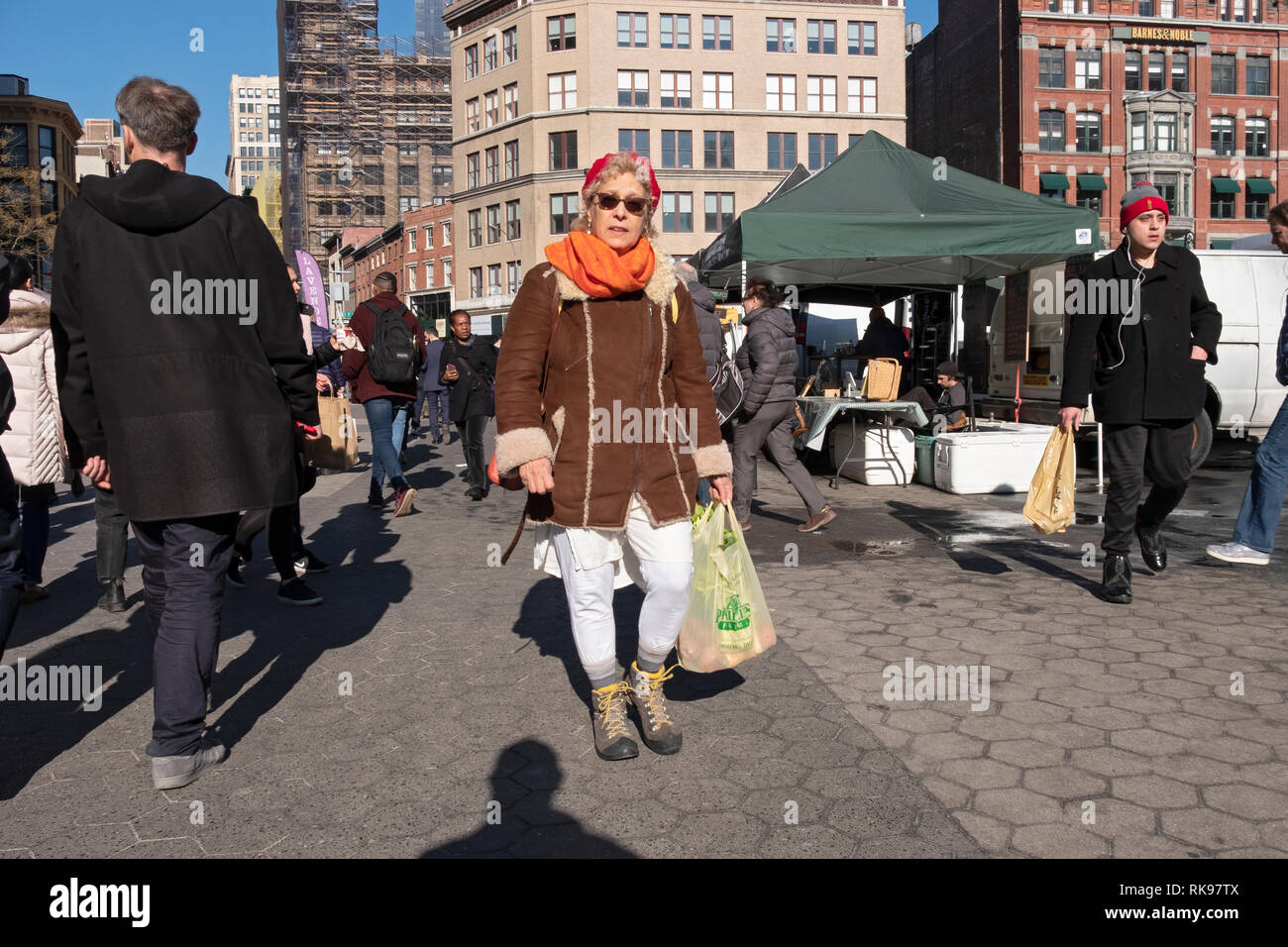 Eine Frau Shopper tragen Einkaufstaschen Spaziergänge durch Th Union Square grünen Markt in Manhattan an einem sonnigen Nachmittag. Stockfoto