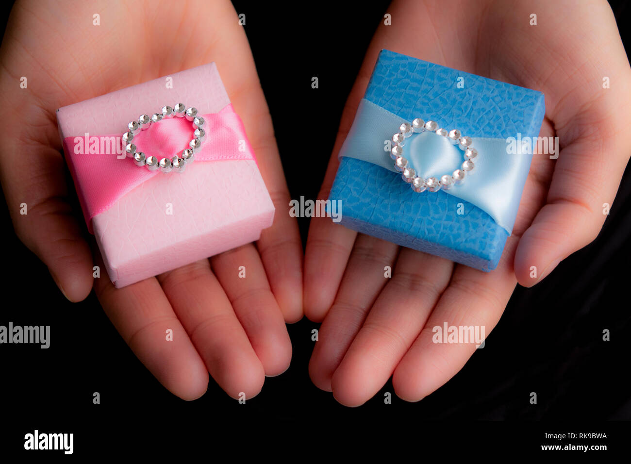 Hände halten Handwerk Geschenk blau und rosa Felder Stockfoto