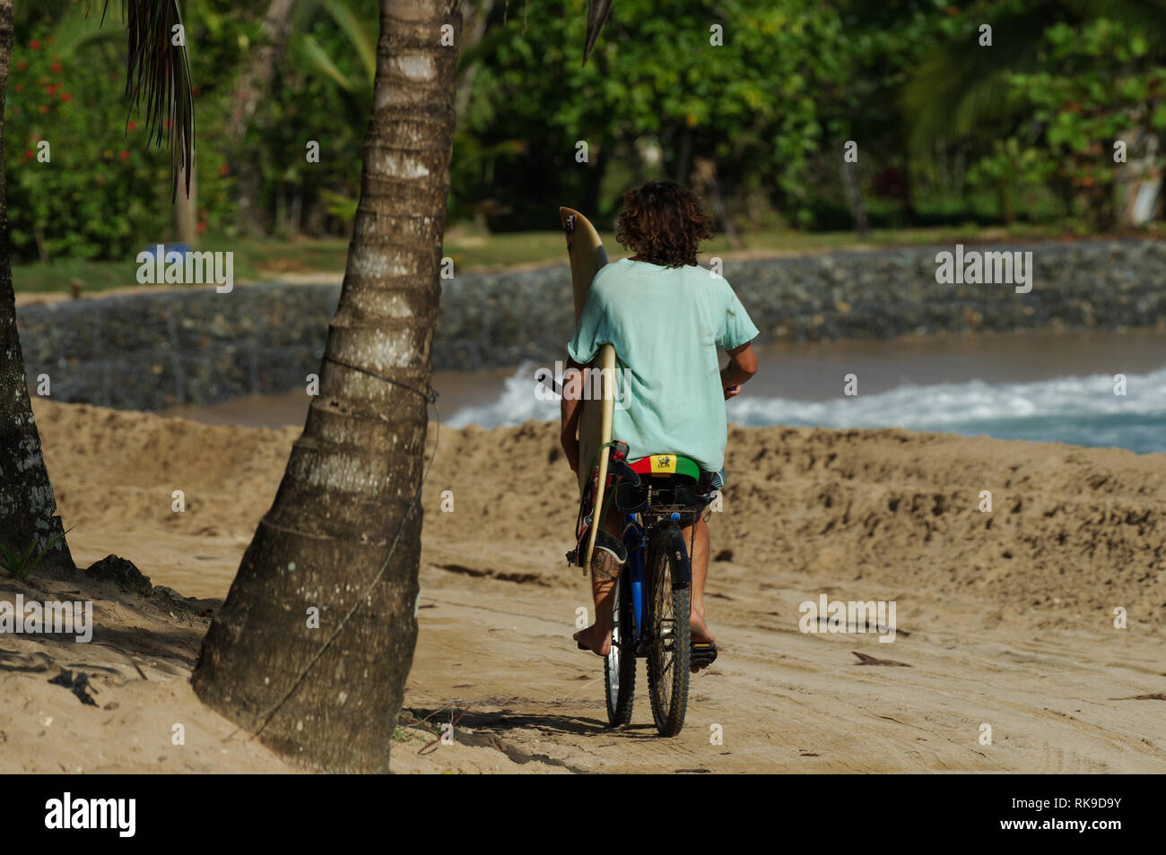 Junger Mann auf dem Fahrrad entlang dem Strand Fahrrad mit einem Surfbrett - Bocas del Toro, Panama Stockfoto