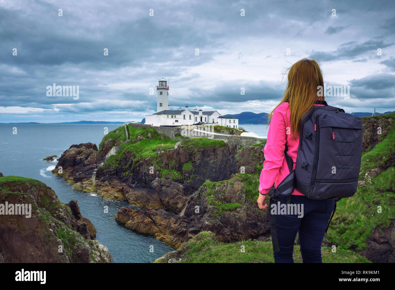 Mädchen mit einem Rucksack auf der Suche der Fanad Head Lighthouse in Irland Stockfoto