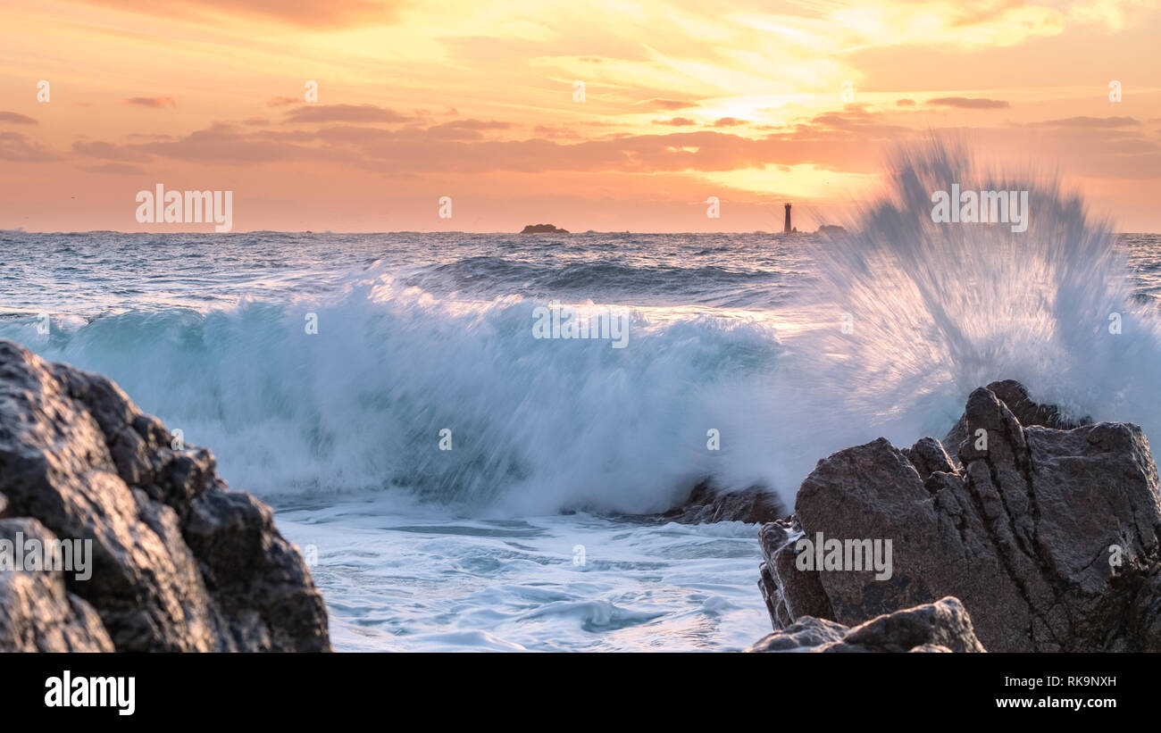 Sonnenuntergang in Guernsey, große Brandung, Leuchtturm in Hanois Stockfoto