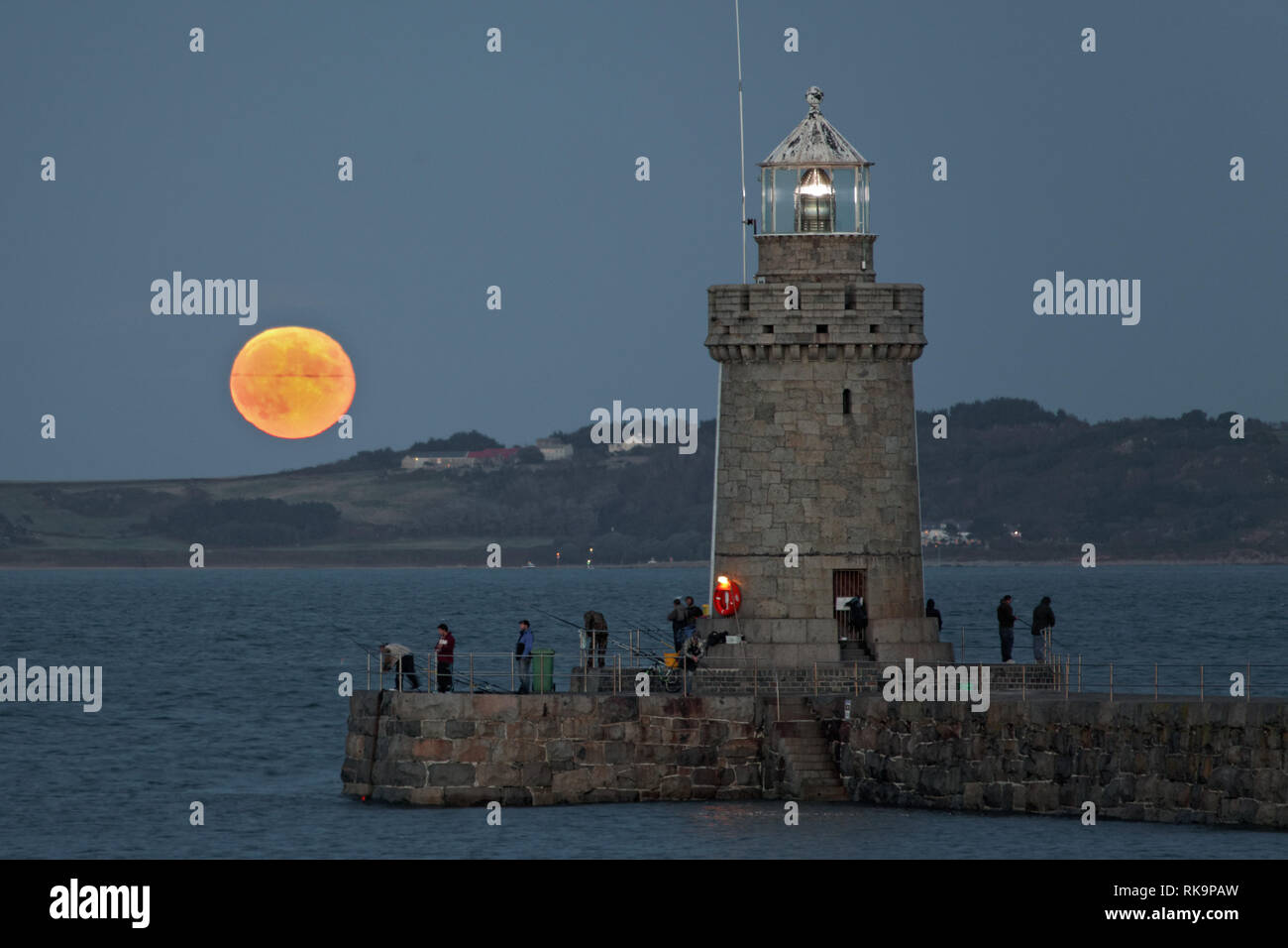Vollmond hinter Herm Insel mit Guernsey breakwater Leuchtturm im Vordergrund steigende Stockfoto