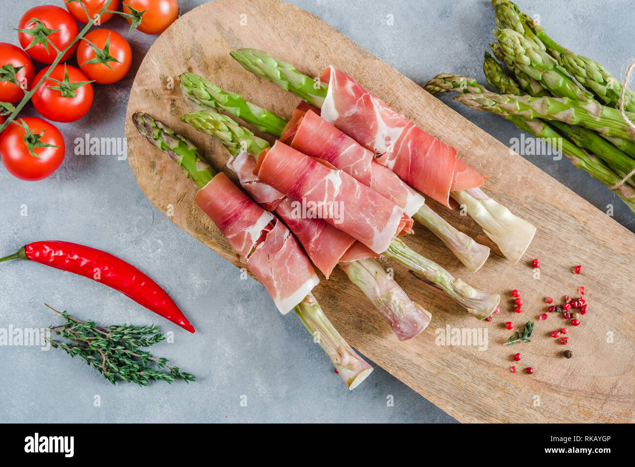 Frische organische Spargel in Schinken auf einem Schneidebrett gewickelt. Stockfoto