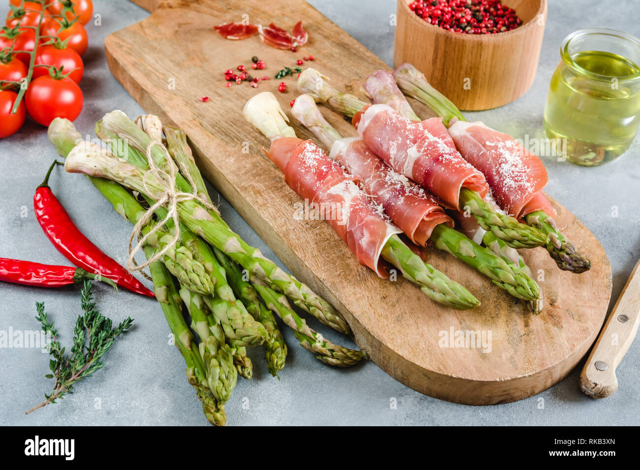 Frische organische Spargel in Schinken auf einem Schneidebrett gewickelt. Stockfoto