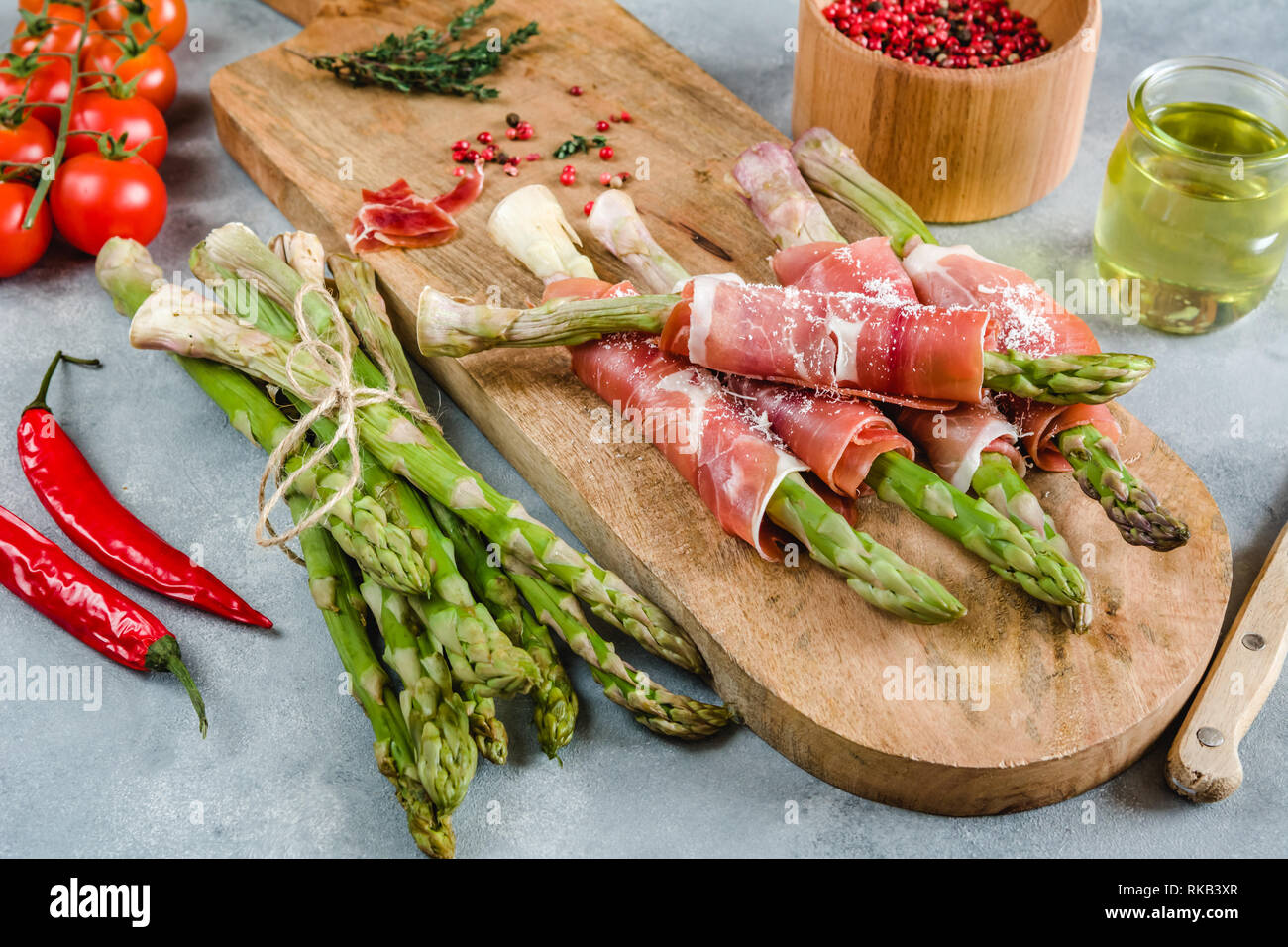 Frische organische Spargel in Schinken auf einem Schneidebrett gewickelt. Stockfoto