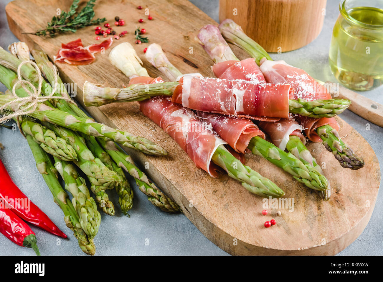 Frische organische Spargel in Schinken auf einem Schneidebrett gewickelt. Stockfoto