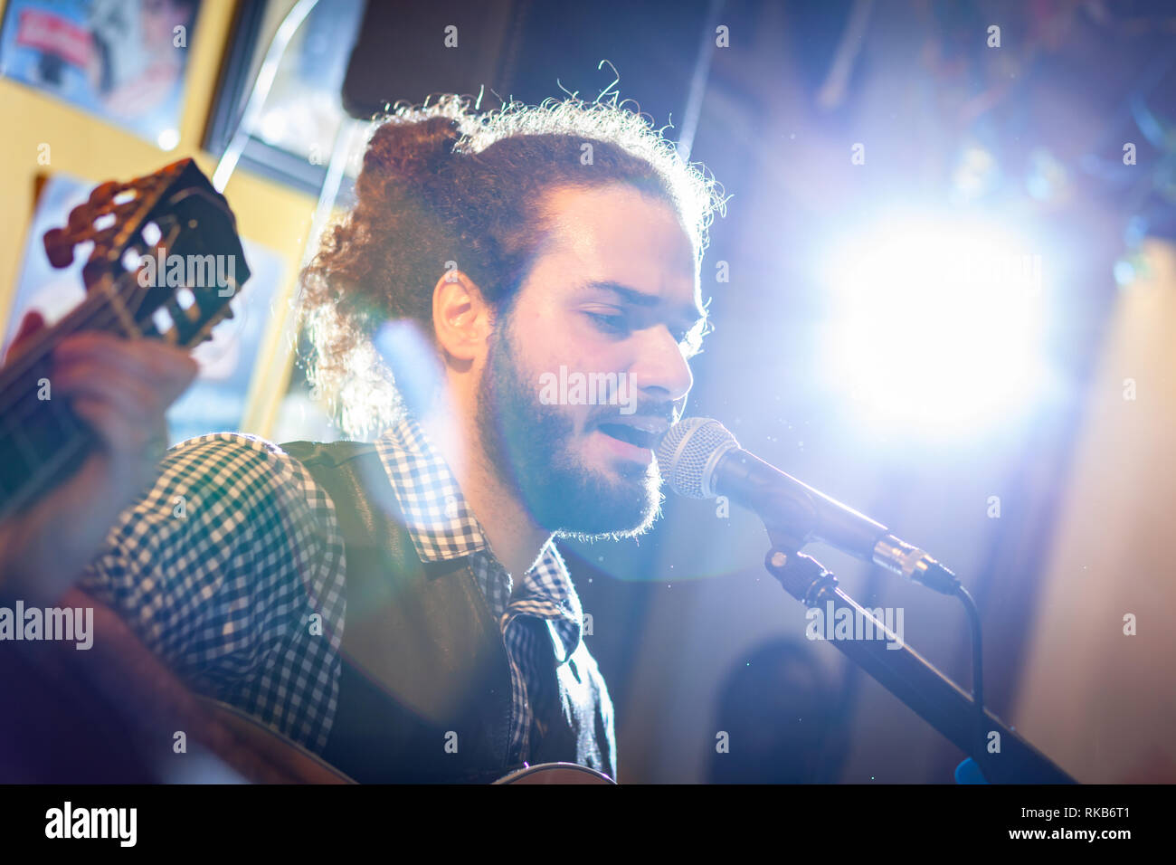 Gitarrist und Sänger während eines musikalischen Leistung. Hintergrundbeleuchtung mit Flair. Stockfoto