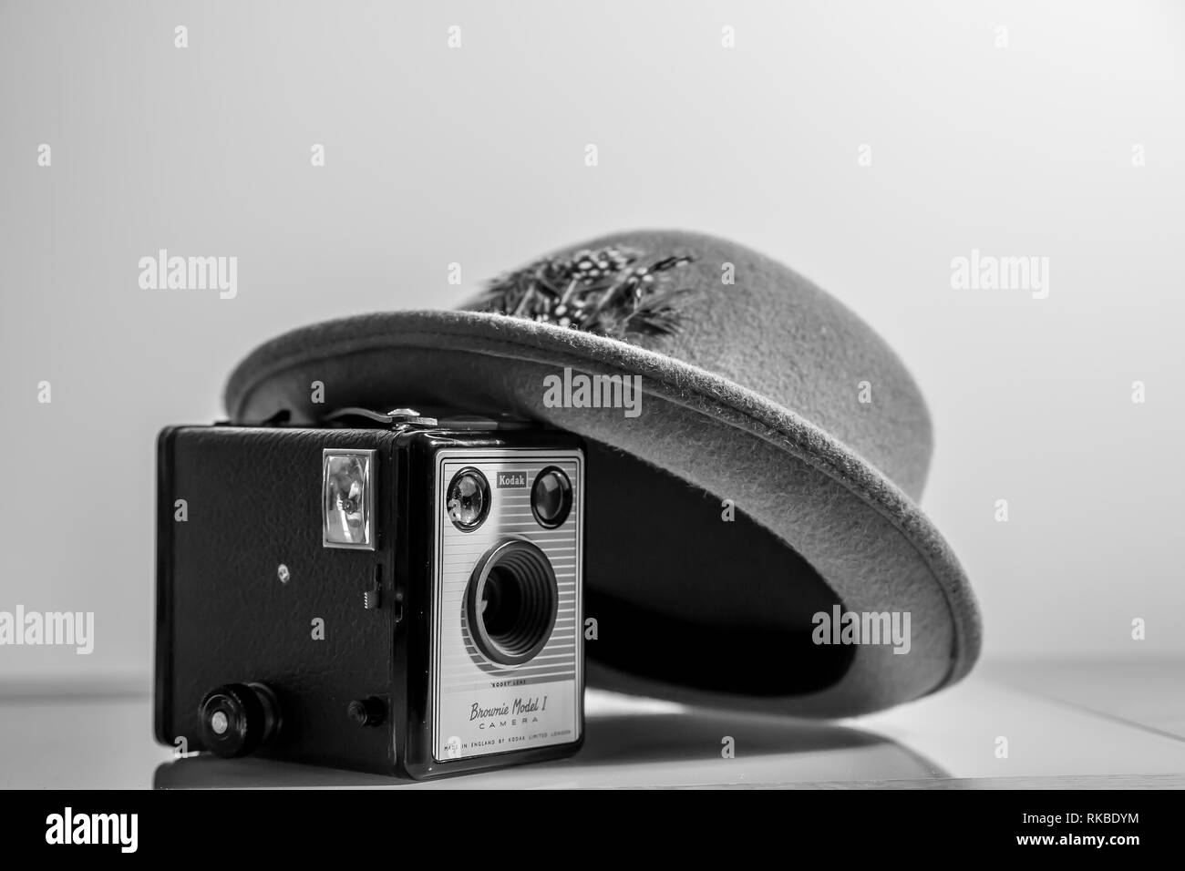 Schwarz-weiß, Nahaufnahme des alten Fedora/Trilby-Hutes der 50er Jahre, angelehnt an die alte, alte Kodak Box Brownie Kamera (Modell 1) aus derselben Zeit. Stockfoto