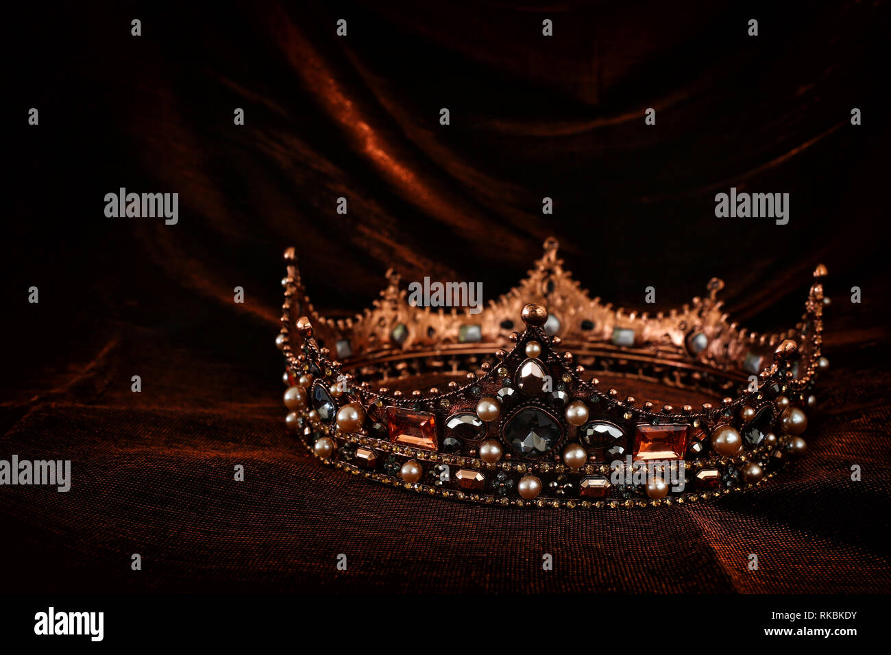 Foto von Gold Crown über Gotische dunkle Seide Hintergrund. Mittelalter Konzept Stockfoto