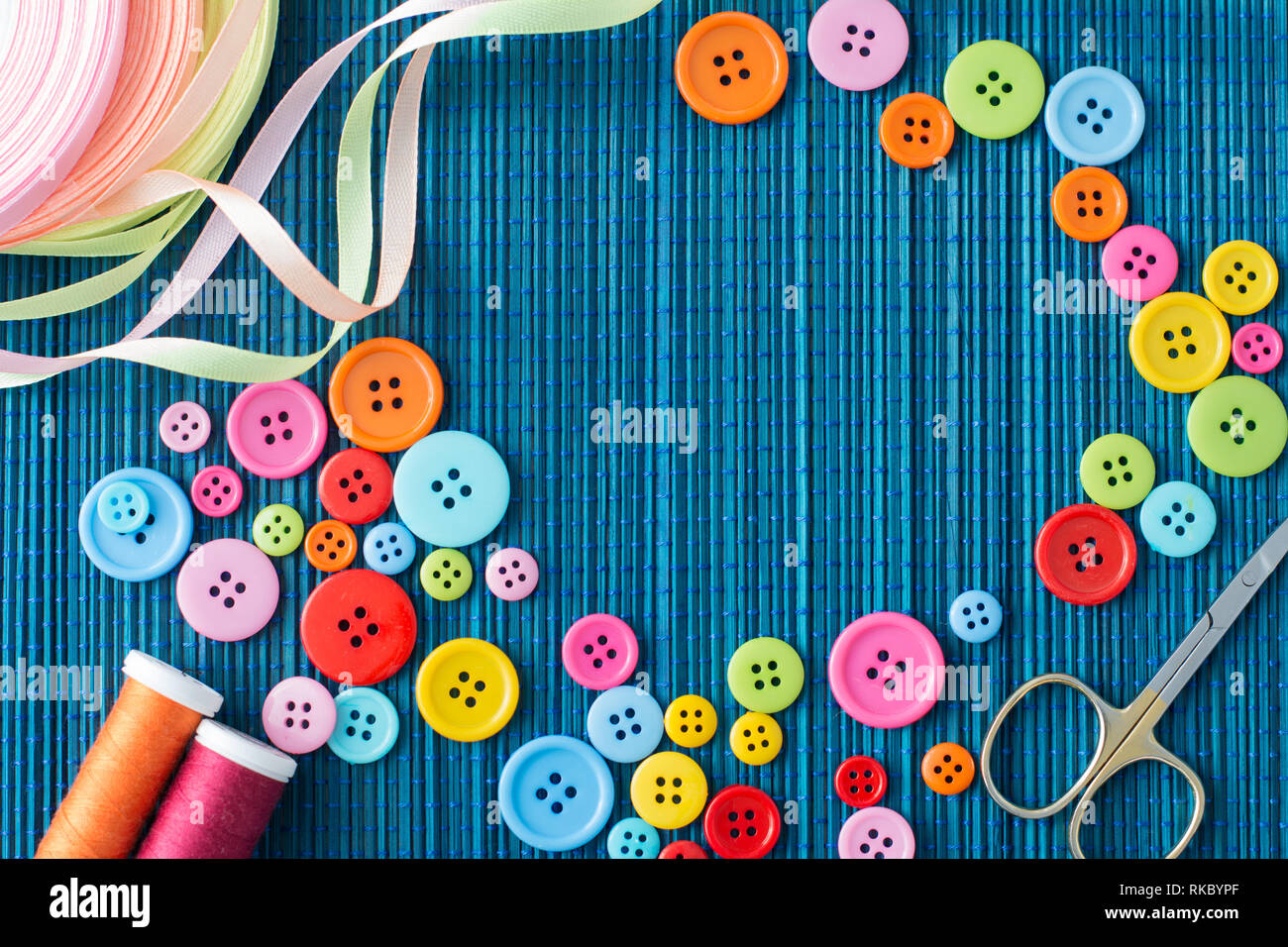 Anpassung der Ausstattung: Viele bunte Buttons, Fäden, Bänder, Scheren auf einem dunkelblauen Strohmatte-text-Raum Stockfoto