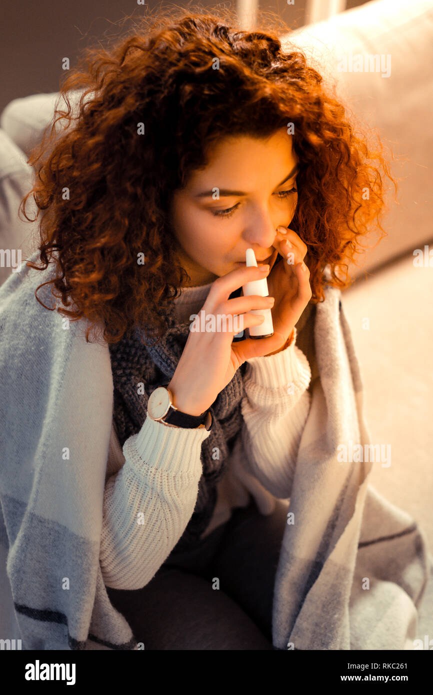 Curly Frau Hand beobachten mit nasenspray nach erkältungsgefahr Stockfoto