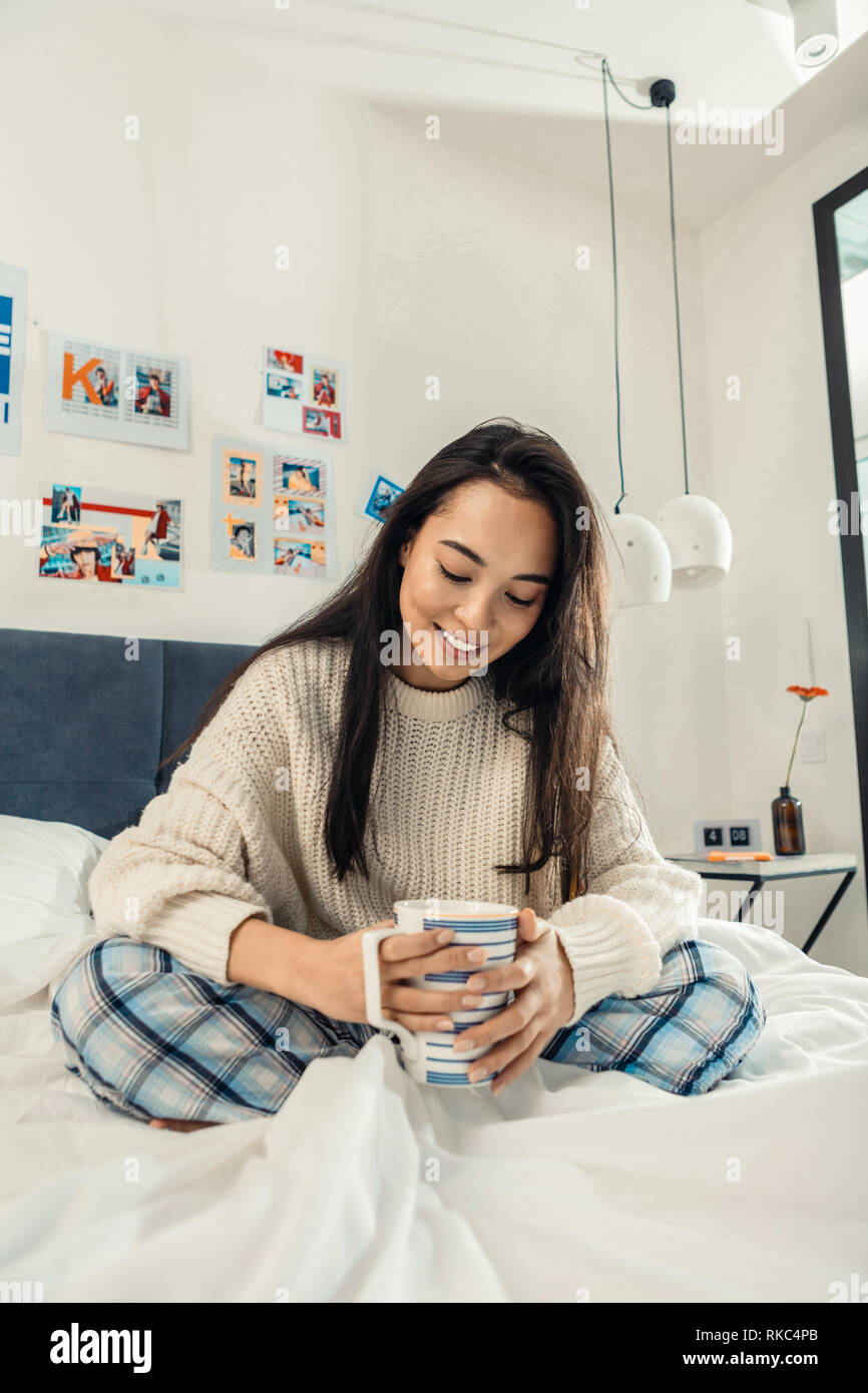 Dunkelhaarige Frau trinkt große Tasse Tee am Morgen Stockfoto