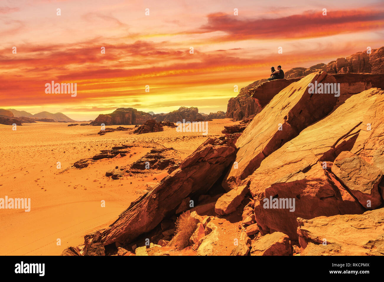 Paar zusammen sitzen auf Wüste Tal Landschaft Sunset Orange Rot reisen Abenteuer exotischen Ort felsige Klippe Stockfoto
