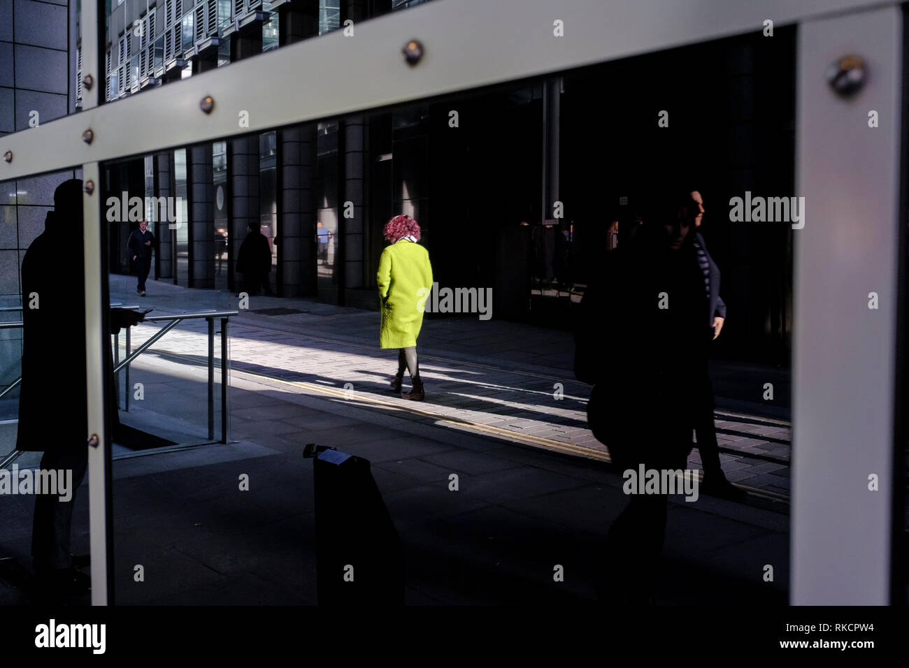 Frau mit grünen Mantel im Bürogebäude aus Glas, London, UK wider Stockfoto