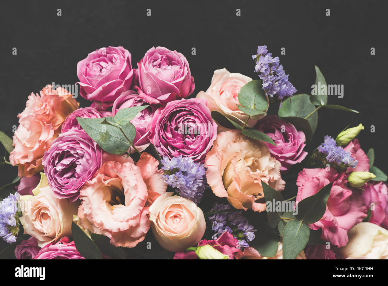 Blumenstrauß aus rosa und lila Päonien mit Eukalyptus auf Schwarz konkreten Hintergrund. Getonten Bild, Pastell Blumenstrauß Stockfoto