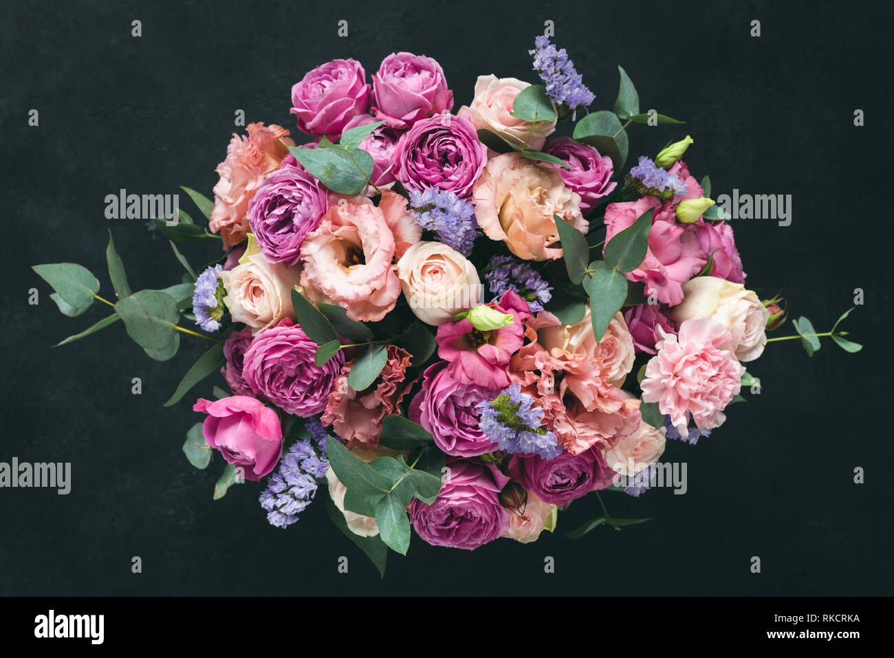 Schönen Blumenstrauß rosa lila Pfingstrosen, Rosen und Eukalyptus auf schwarzem Hintergrund isoliert. Ansicht von oben Stockfoto