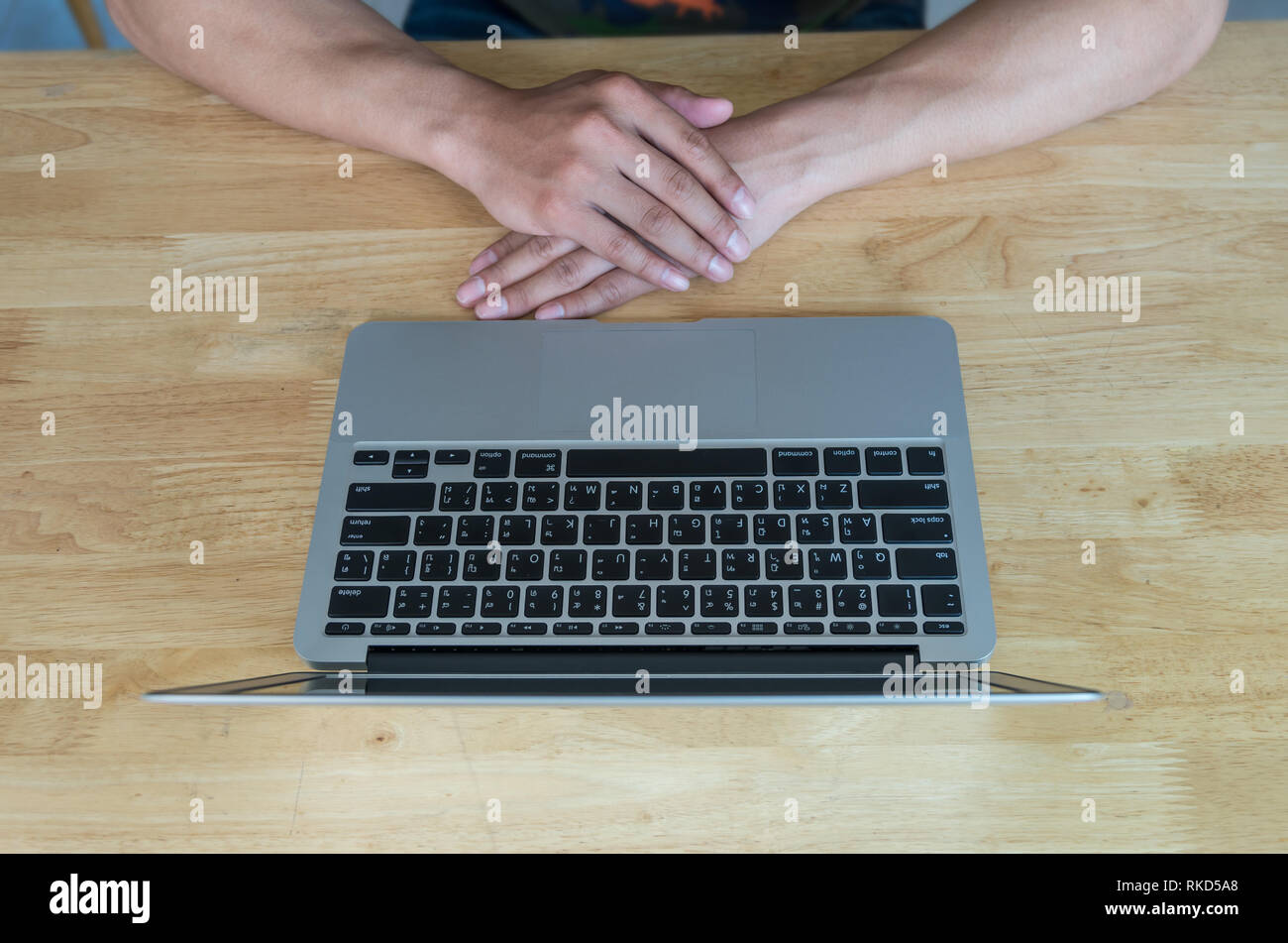 Blick von oben auf die Hand, die mit Laptop auf dem hölzernen Tisch, Geschäftskonzept, englisch und thai Text auf der Tastatur Stockfoto