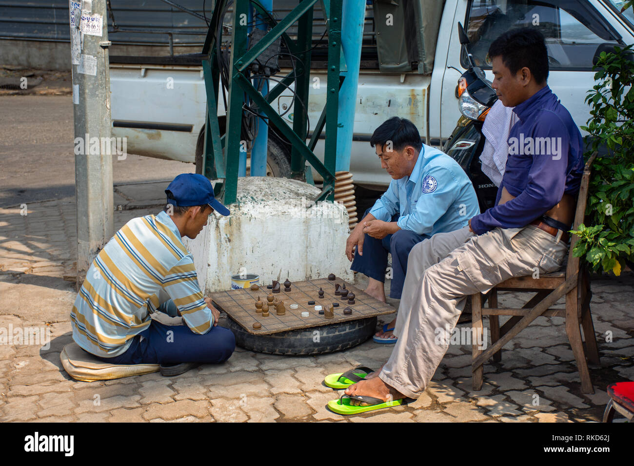 Eine Gruppe von asiatischen Männer spielen eine Machen brettspiel schach auf der Straße, Kambodscha. Stockfoto