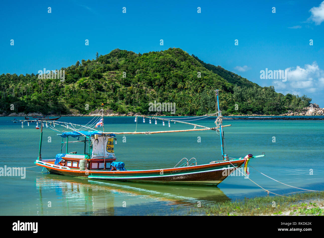 Ein Thai Long tail Boot, verankert in einem schönen Island Bay Lage an der Küste. Stockfoto