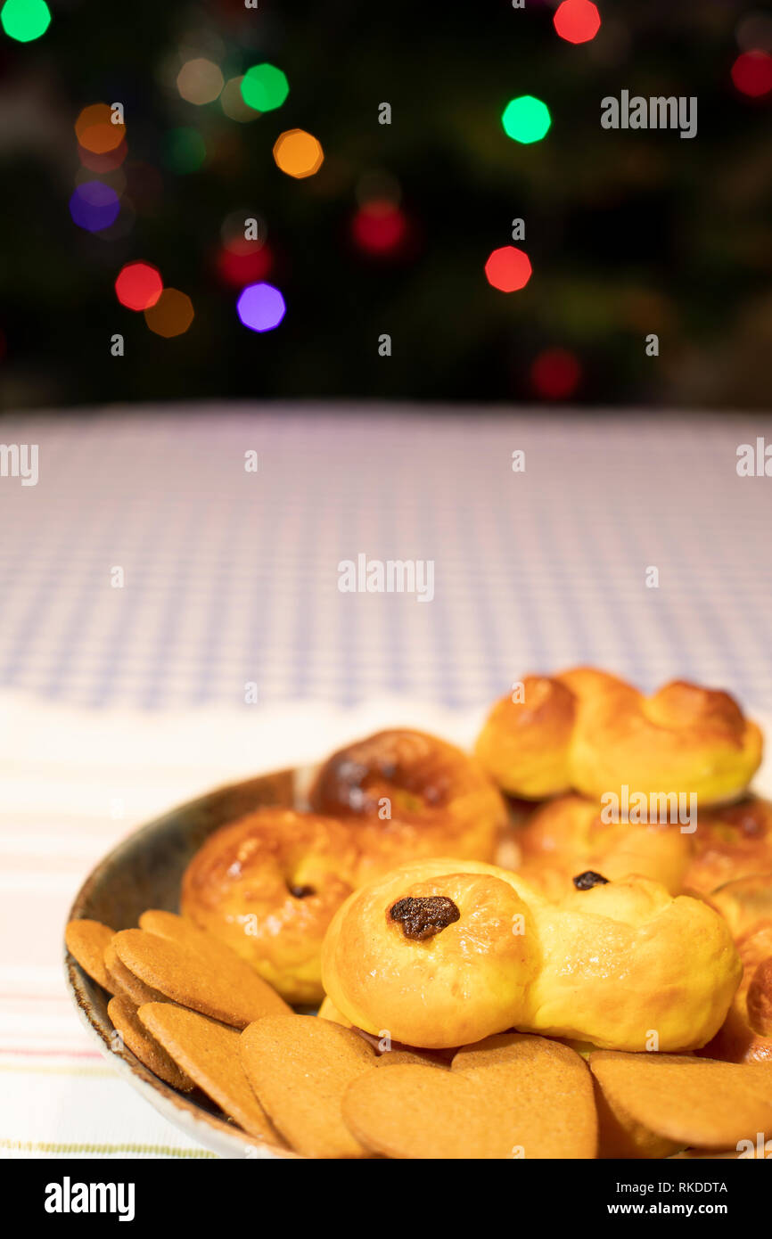 Eine Platte der traditionellen schwedischen Safran Brot und Ginger Snaps mit unscharfen farbige Weihnachtsbaumbeleuchtungen im Hintergrund. Stockfoto