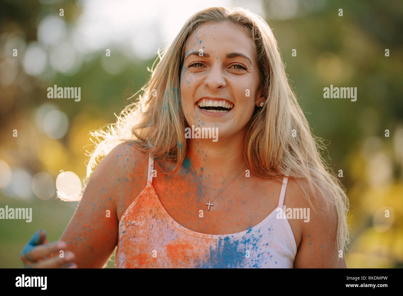 Lächelnde Frau mit Farben spritzte auf Ihren Körper spielen Holi. Glückliche Frau holi Spielen mit Puder Farben im Freien. Stockfoto