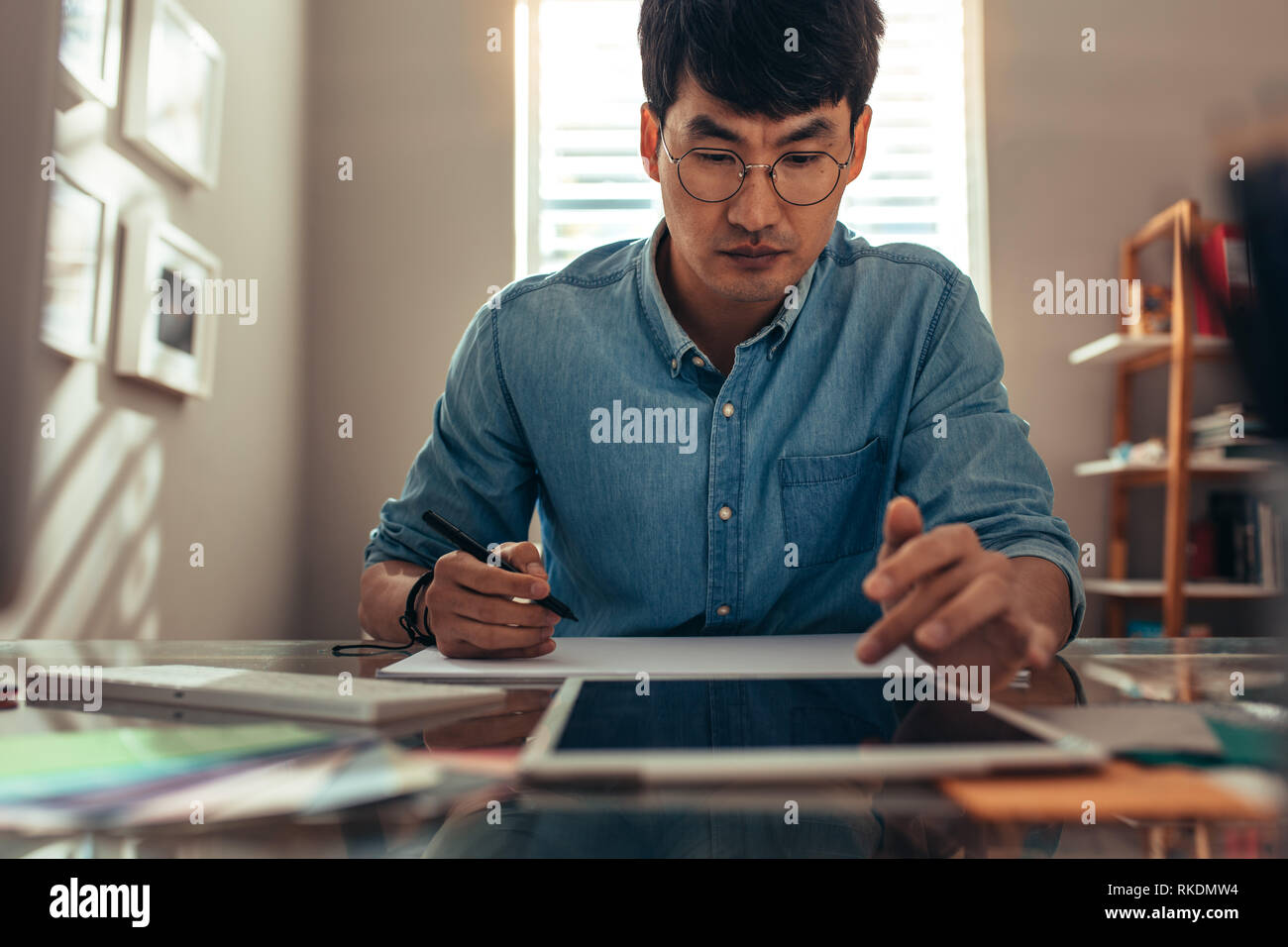 Kreative Menschen arbeiten im Büro mit Tablet Pcs und dämmern Buch. Männliche Interior Designer, eine Zeichnung auf Buchen Sie während der Einnahme von digitalen ta Stockfoto