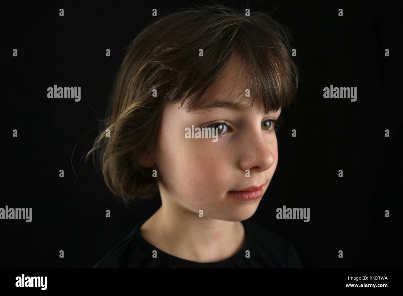 Porträt eines Green Eyed braunhaarige Mädchen von der Seite gegen einen schwarzen Hintergrund zu sehen Stockfoto